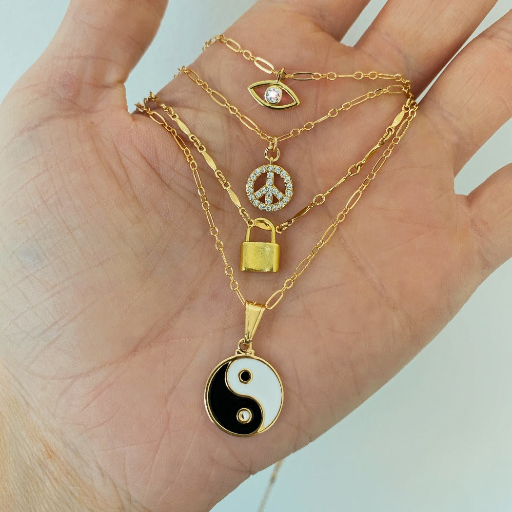 Rachel Mulherin CZ peace sign gold necklace layered with evil eye, yin yang and lock necklaces